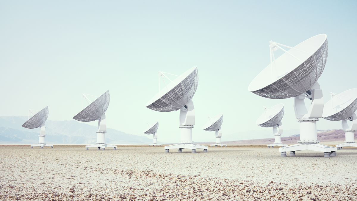 A field of large satellite dishes points toward the sky in a barren landscape, symbolizing global communication and data transmission.