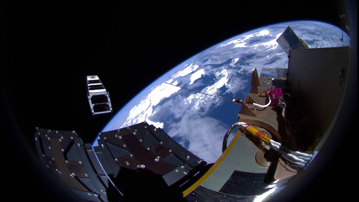 View of Earth and a small satellite being deployed from a spacecraft, captured in space.