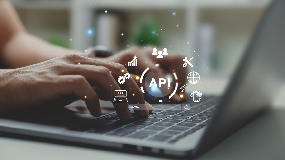 A close-up of hands typing on a laptop keyboard with floating icons related to APIs, such as gears, graphs, and network symbols, representing software development and integration.