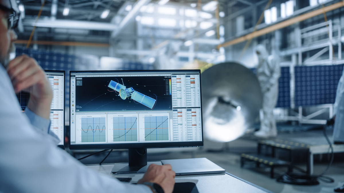 Engineers at an aerospace agency monitors satellite design and orbital trajectory data on computer screens in a high-tech lab.