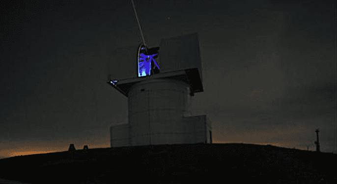 The optical ground station at the National Observatory of Athens, with a laser beam emitting from its telescope dome against a night sky.