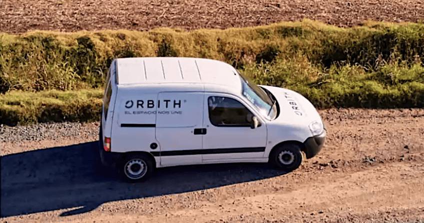 A white van with the Orbith logo drives down a rural dirt road.