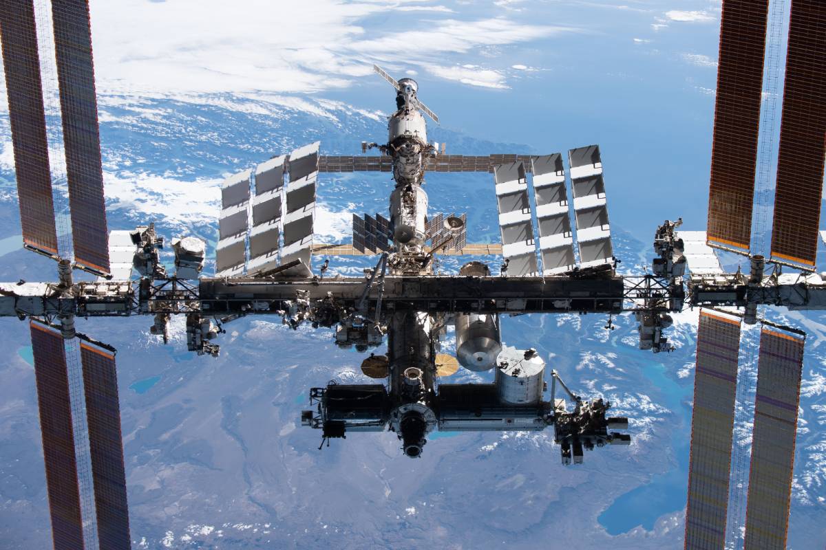 The International Space Station (ISS) orbiting Earth, featuring its large solar arrays, modular structure, and detailed view of the planet's surface below.