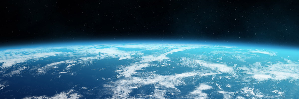 A view of Earth from space, showing the blue ocean, white clouds, and the thin atmospheric layer against the blackness of space.