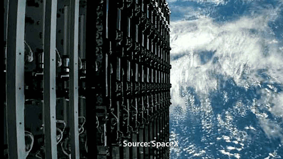 A close-up view of a SpaceX Starlink satellite stack in orbit, with Earth’s surface visible in the background.